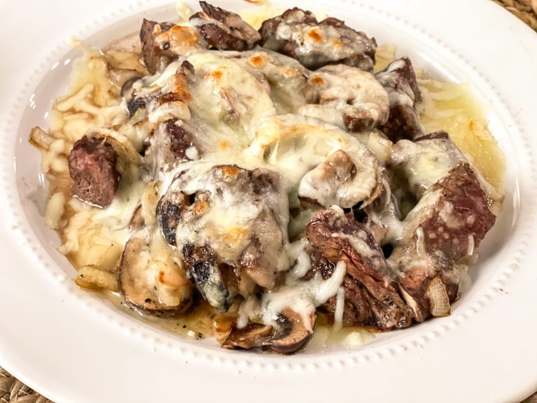 Chunks of steak covered in mushrooms, onions, and melted cheese. 