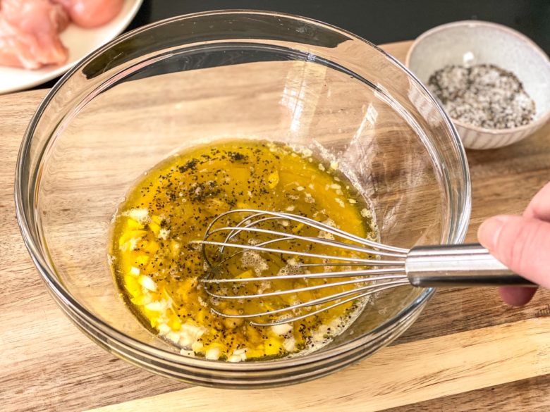 Ground mustard marinade in a mixing bowl with a whisk. 