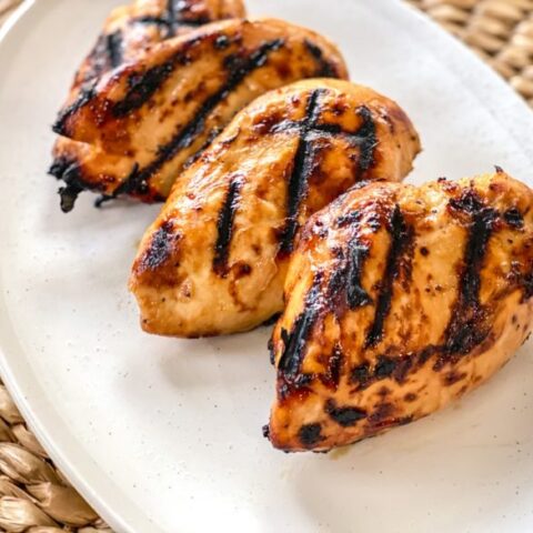 Chicken breasts with mustard and brown sugar marinade on a white plate.