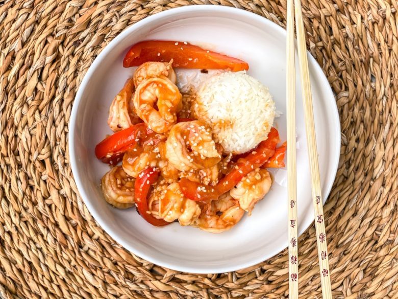 Szechuan shrimp with white rice in a bowl with chopsticks. 