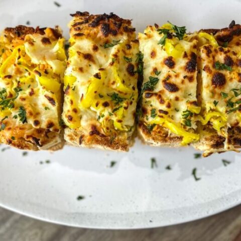 Cheese bread with banana peppers on a plate.