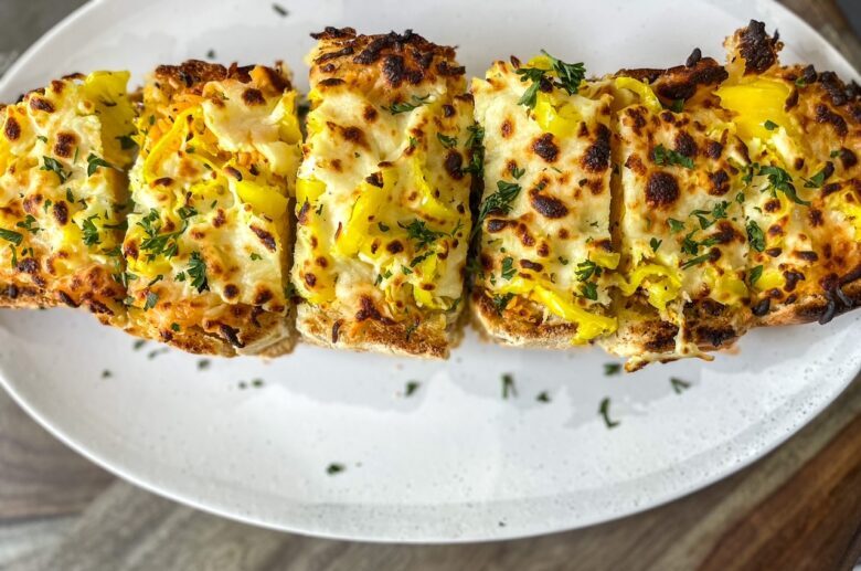 Cheese bread with banana peppers on a plate. 